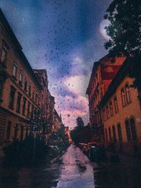 Road amidst buildings against sky during rainy season