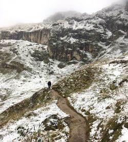 Man standing on rock by mountain against sky