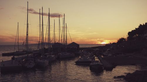 Boats moored on sea against sky during sunset