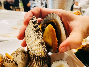 Cropped hand of person holding cooked shellfish