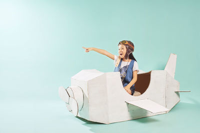 Smiling girl sitting in toy airplane over blue background