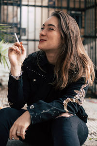 Young woman sitting on cigarette