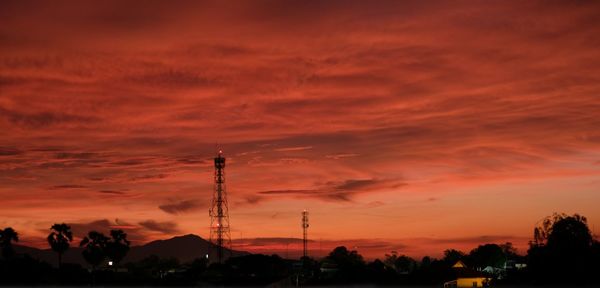 Silhouette of communications tower against cloudy sky during sunset