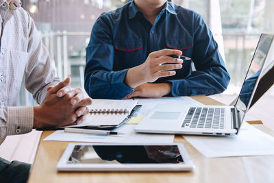 Midsection of man using mobile phone while sitting on table