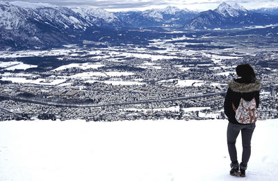 Rear view of woman standing on snowcapped mountain