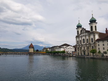 View of buildings by river against sky