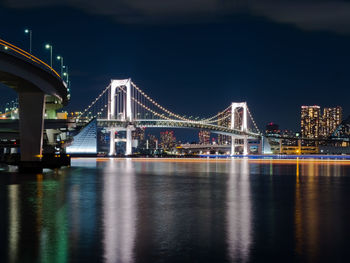 Illuminated bridge over river at night