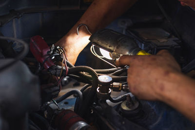 Cropped hands of mechanic repairing car