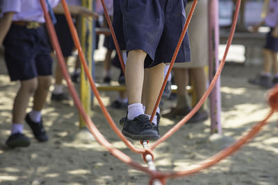 Low section of student standing on rope at playground