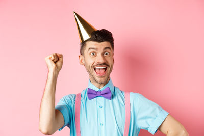 Portrait of young man against pink background