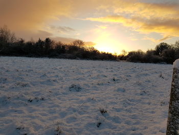 Scenic view of snow field against sky during sunset