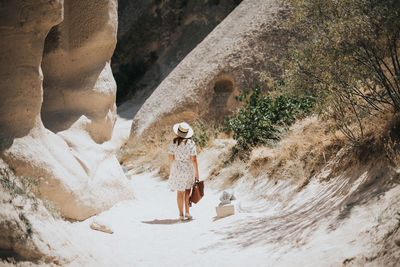 Rear view of woman walking by rock formation at desert