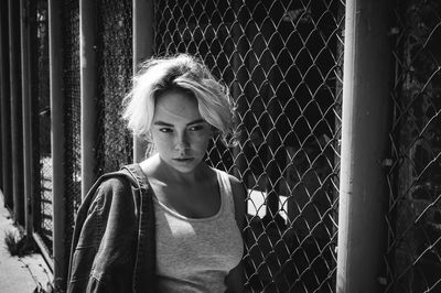 Young woman leaning on chainlink fence