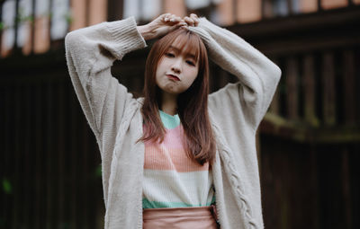 Midsection of young woman standing against wall