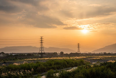 Electricity pylon on field against sky during sunset