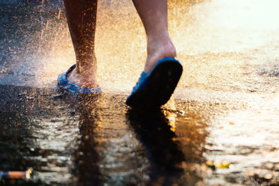 Low section of man walking on wet street