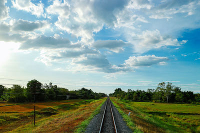 Empty railroad track amidst field against sky