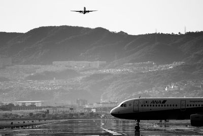 Airplane flying over cityscape against sky