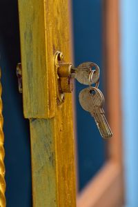 A pair of keys hanging on the door with yellow paint