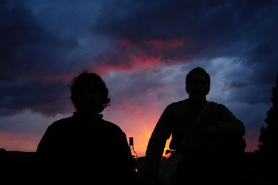 Silhouette men against cloudy sky during sunset