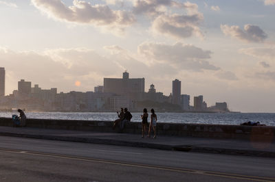 People on road against sky during sunset