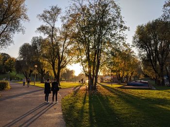 People walking on road against sky during autumn