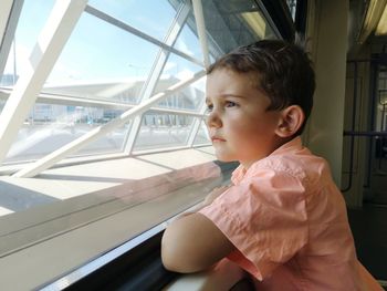 Cute boy looking through window while sitting in subway train