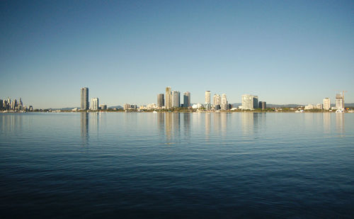 Sea by buildings against clear sky