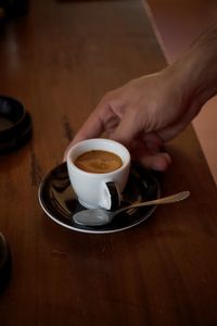 Cropped hands of woman holding coffee on table