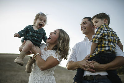 Man looking at girl playing with mother while standing on field