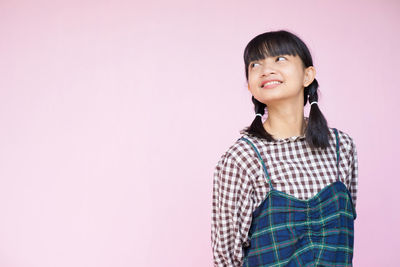 Portrait of teenage girl standing against wall