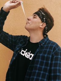 Portrait of a young man looking away while standing against wall