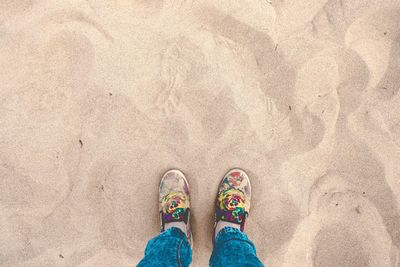 Low section of person standing on sand