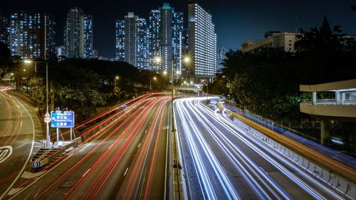 Light trails on road against illuminated buildings in city