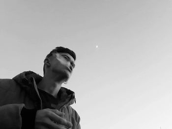 Low angle view of young man against clear sky