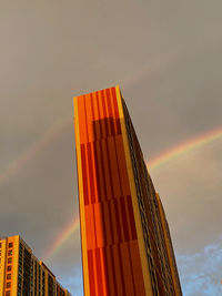 Low angle view of rainbow over building against sky