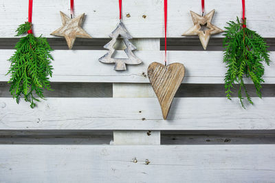 Christmas ornaments hanging against white wooden fence