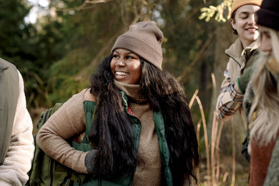 Happy young woman wearing warm clothing while looking at friend