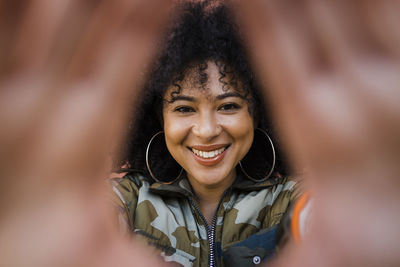 Happy young woman making frame with hand in front of face