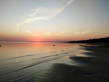 Scenic view of beach against sky at sunset