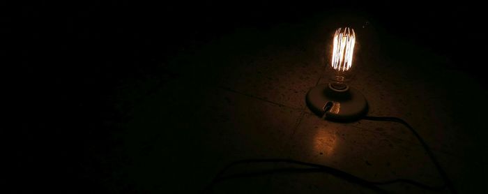 Close-up of illuminated lamp over black background