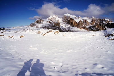 Low section of person on snowcapped mountain against sky