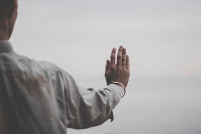 Midsection of man gesturing against sky