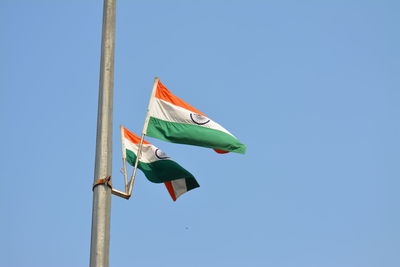 Low angle view of flag against clear blue sky