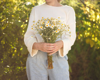 Midsection of woman holding flowering plant