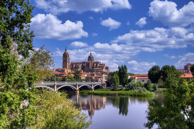 Arch bridge over river amidst buildings against sky