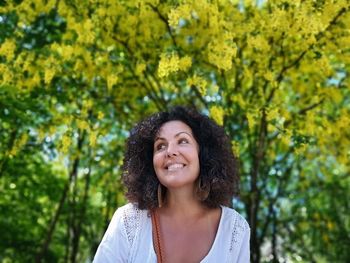 Smiling woman looking away against trees