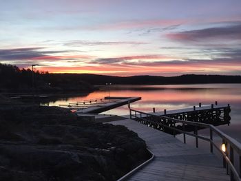 Pier over lake against sky at sunset