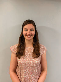 Portrait of young woman standing against wall