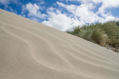 Sand dunes at beach against sky